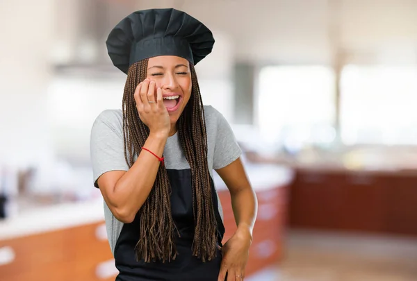 Portrait of a young black baker woman laughing and having fun, being relaxed and cheerful, feels confident and successful