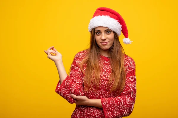 戴圣诞老人帽子的年轻妇女用手指指向旁边 — 图库照片
