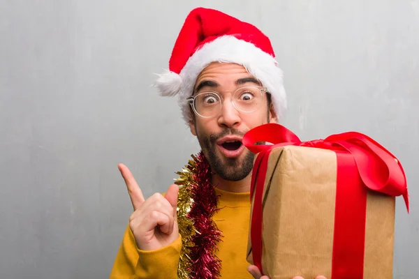 Junger Mann Sitzt Mit Weihnachtsgeschenken Und Zeigt Mit Dem Finger — Stockfoto