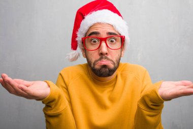 Kutlama Noel günü şüphe ve omuzlarında shrugging hediyeler tutan genç adam