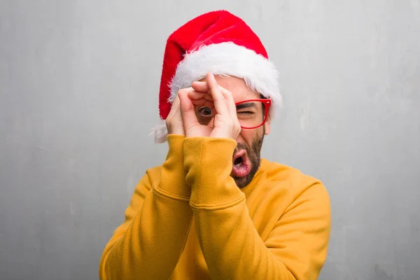 若い男 スパイグラスのジェスチャーを作る贈り物を持って祝うクリスマス — ストック写真