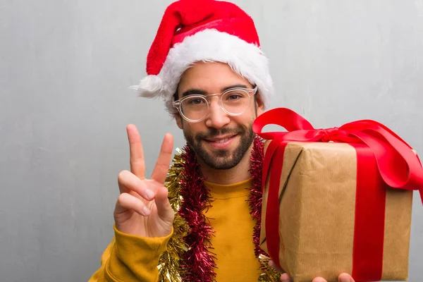 Joven Sentado Con Regalos Celebrando Navidad Mostrando Número Dos — Foto de Stock