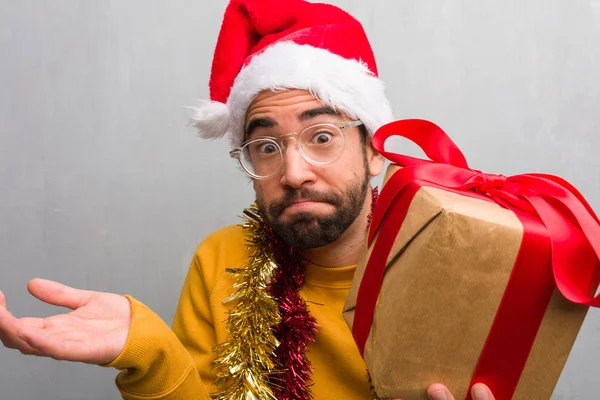 Молодий Чоловік Сидить Подарунками Святкуючи Різдво Сумнівається Відкидає Плечі — стокове фото