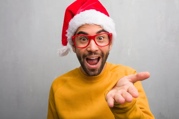 Young man celebrating christmas day holding gifts reaching out to greet someone