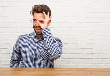 Neşeli ve kendine güvenen yapıyor Tamam jest, heyecanlı ve çığlık, kavram onayı ve başarı oturan genç beyaz adam