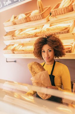 Çalışma, bir tahıl ekmek sopa, o hissediyor çünkü işini seviyor güzel tutan genç afro kadın baker.