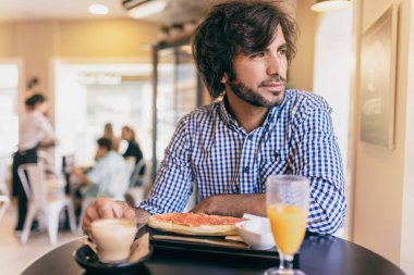 Genç modern insan café'de kahvaltı hakkında bir fikir düşünce pencereden bakıyor.