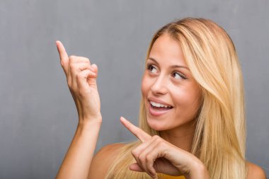 Yüz closeup, sürpriz bir şey, doğal ve rahat sunan gülümseyen tarafına işaret doğal genç sarışın bir kadın portresi