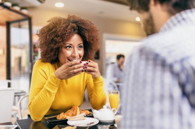 Genç trendy café'de bir kahve ve çay içme, bir kruvasan yemek ve duygu mutlu çift.