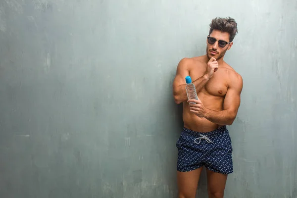 Young Athletic Man Wearing Swimsuit Grunge Wall Thinking Looking Confused — Stock Photo, Image