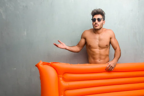 Young Athletic Man Wearing Swimsuit Grunge Wall Doubting Shrugging Shoulders — Stock Photo, Image