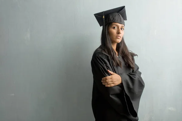 Young graduated indian woman against a wall crossing his arms, serious and imposing, feeling confident and showing power