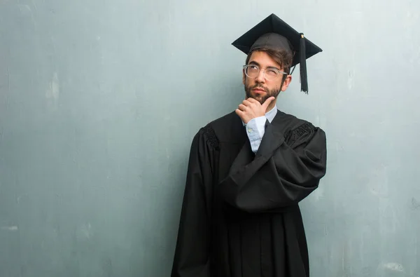 若い疑うことコピー スペースとグランジ壁男を卒業 混乱し アイデアや何かを心配して考えて — ストック写真