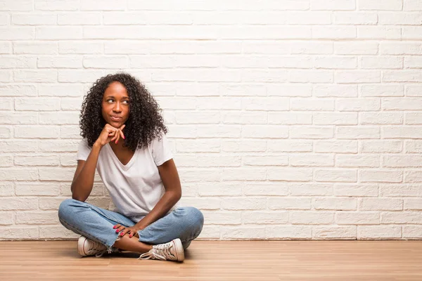 Νεαρή Μαύρη Γυναίκα Που Κάθεται Στο Ξύλινο Πάτωμα Σκέψης Και — Φωτογραφία Αρχείου