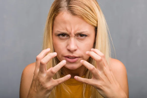 Face closeup, portrait of a natural young blonde woman very angry and upset, very tense, screaming furious, negative and crazy