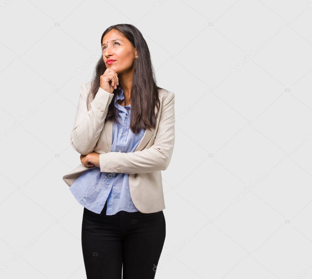 Young business indian woman doubting and confused, thinking of an idea or worried about something