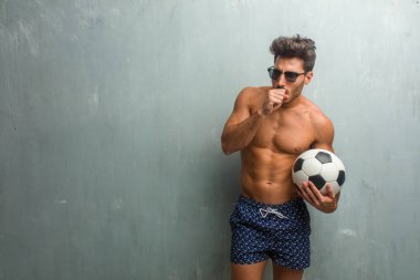Young athletic man wearing a swimsuit against a grunge wall with a sore throat, sick due to a virus, tired and overwhelmed clipart