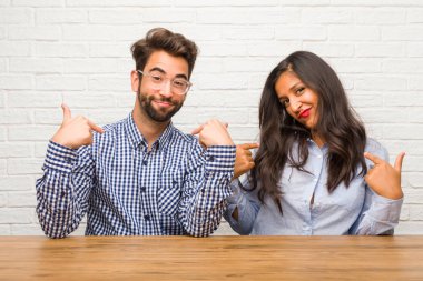 Young indian woman and caucasian man couple proud and confident, pointing fingers, example to follow, concept of satisfaction, arrogance and health clipart