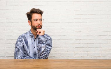 Şüphe ve karışık, düşünme, bir fikir ya da bir şey hakkında endişeli oturan genç beyaz adam