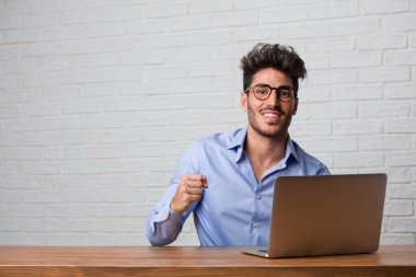 Silah, bir zafer ya da başarı, piyango kazanan kutluyor yükselterek oturma ve çalışma üstünde a laptop çok mutlu ve heyecanlı, Genç iş adamı