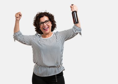 Orta yaşlı kadın mutlu ve eğlenceli bir şişe bira, holding, iş, bir futbol izlemek için hazır yoğun bir günün ardından iyi geldi televizyonda maç