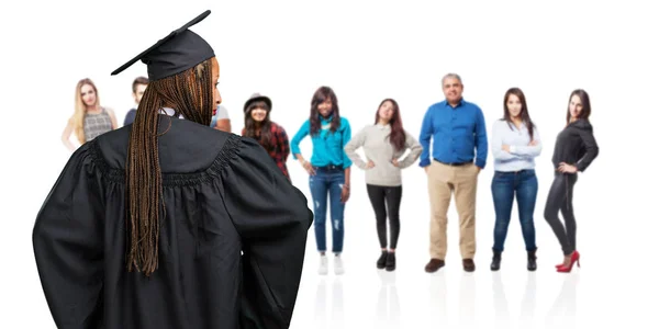 Young graduated black woman wearing braids showing back, posing and waiting, looking back