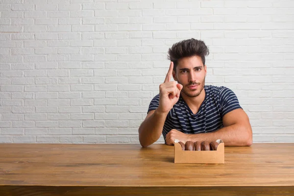 Young Handsome Natural Man Sitting Table Showing Number One Symbol — Stock Photo, Image