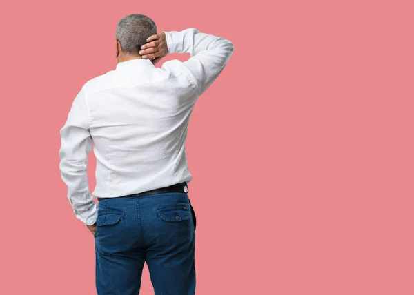 Middle aged man showing back, posing and waiting, looking back