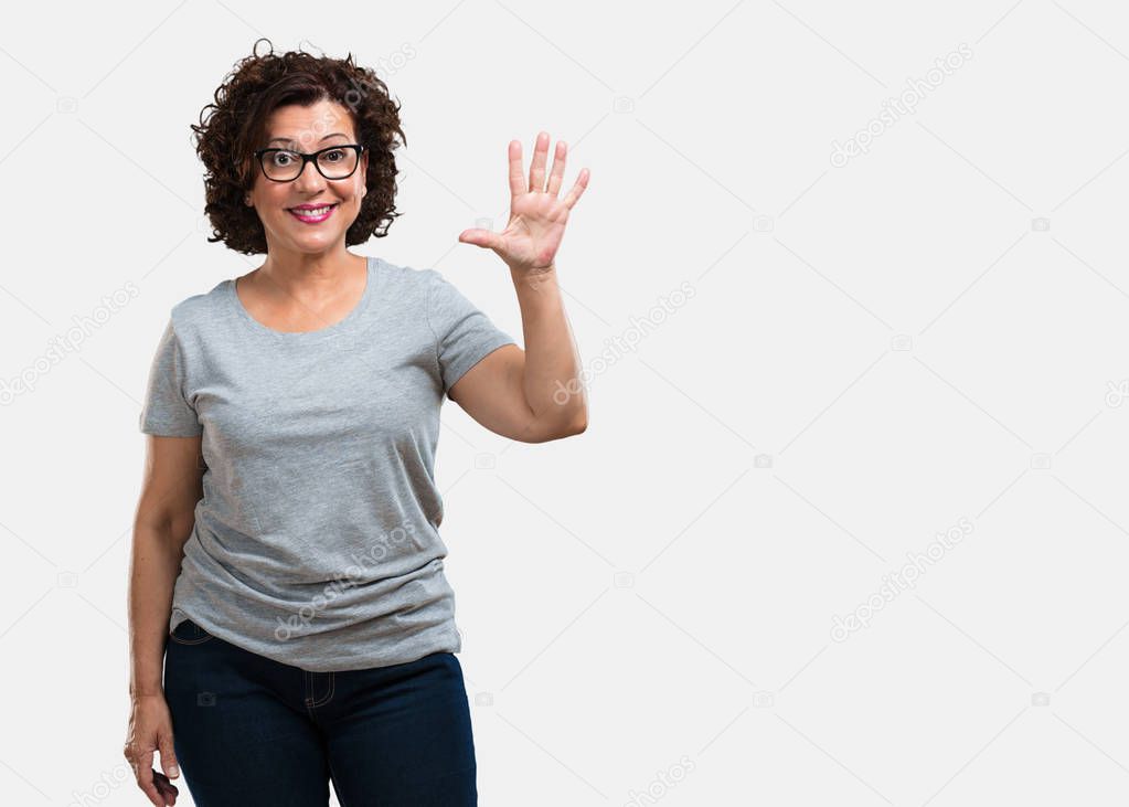 Middle aged woman showing number five, symbol of counting, concept of mathematics, confident and cheerful