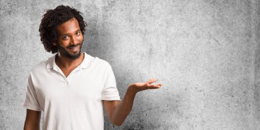 Yakışıklı elleriyle bir şey tutan, bir ürün, gülümseyen ve neşeli gösterilen, hayali bir nesne sunan Amerikan Afrika