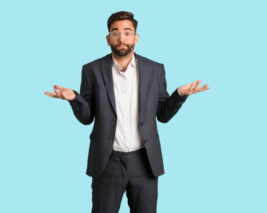 Şüphe ve omuzlarında shrugging genç yakışıklı iş adamı