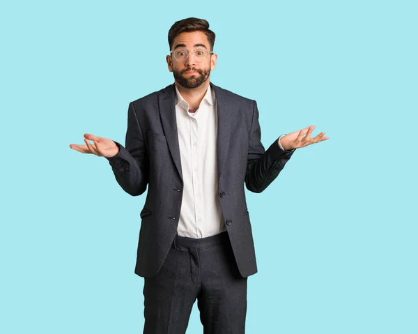Şüphe ve omuzlarında shrugging genç yakışıklı iş adamı