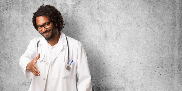 Handsome african american medical doctor reaching out to greet someone or gesturing to help, happy and excited