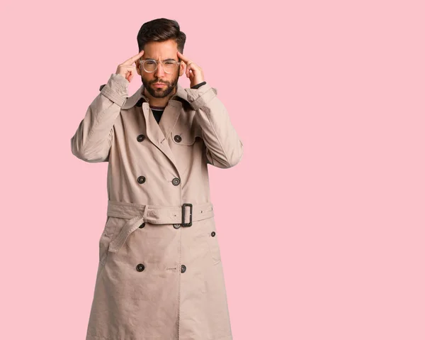 Young man wearing trench coat doing a concentration gesture