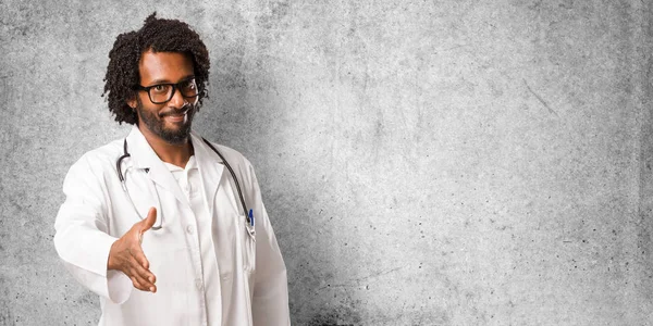 Handsome african american medical doctor reaching out to greet someone or gesturing to help, happy and excited