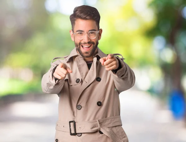 Young man wearing trench coat cheerful and smiling
