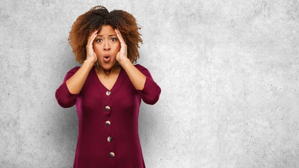 Young black afro woman surprised and shocked