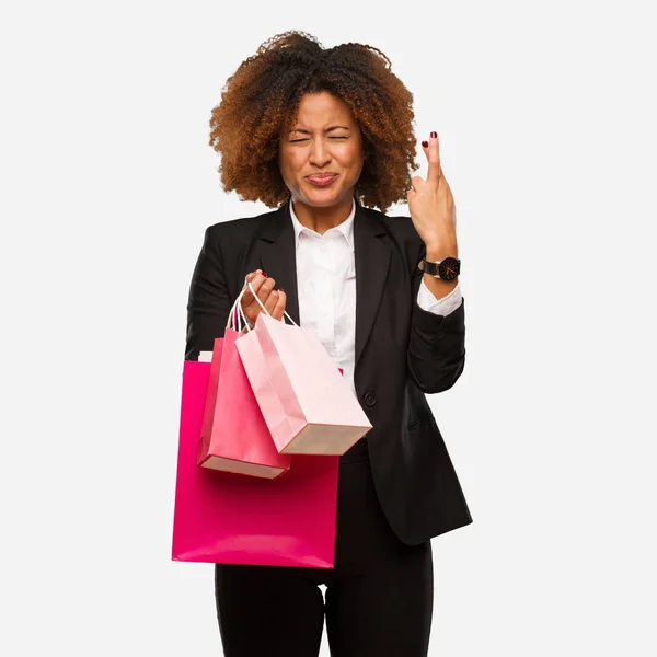 Young Black Woman Holding Shopping Bags Crossing Fingers Having Luck — Stock Photo, Image