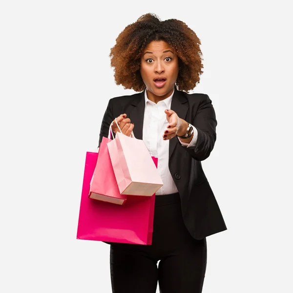 Young black woman holding shopping bags reaching out to greet someone