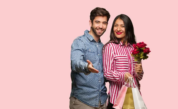 Young couple in valentines day reaching out to greet someone