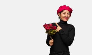 Young woman in valentines day pointing to the side with finger