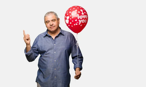 Middle aged man celebrating valentines day pointing to the side with finger