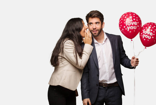 Young couple in valentines day whispering gossip undertone