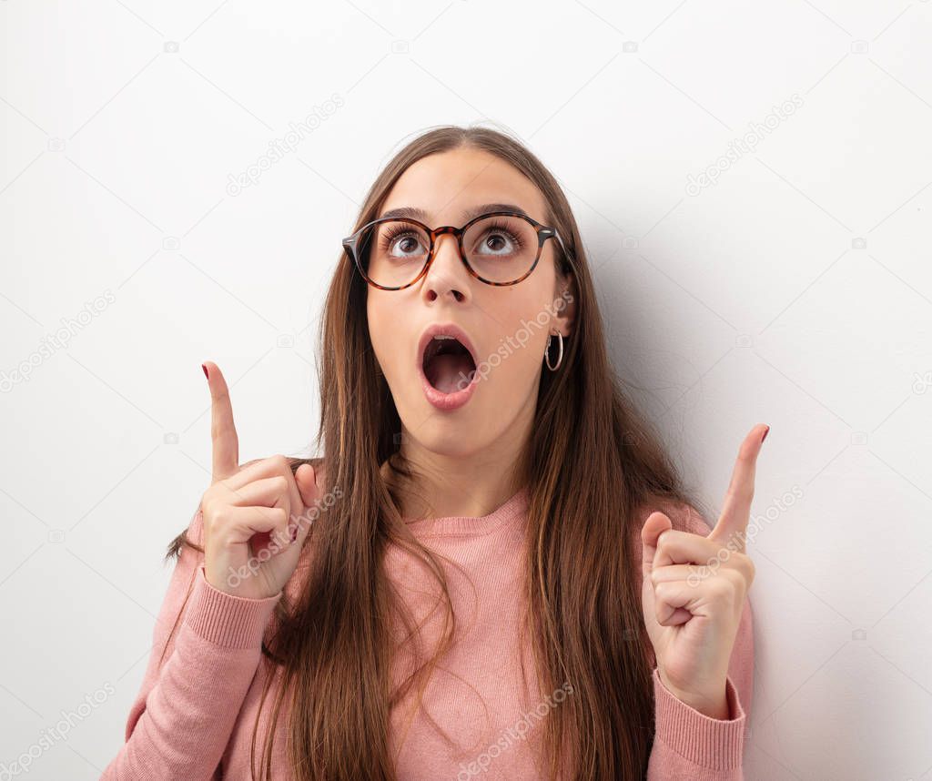 Young cute woman surprised pointing up to show something