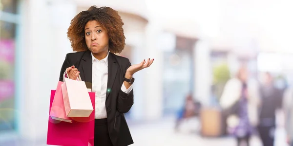 Joven Mujer Negra Sosteniendo Bolsas Compras Dudando Encogiéndose Hombros — Foto de Stock