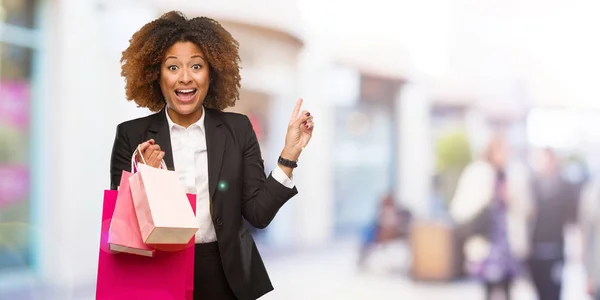 Young Black Woman Holding Shopping Bags Pointing Side Finger — Stock Photo, Image