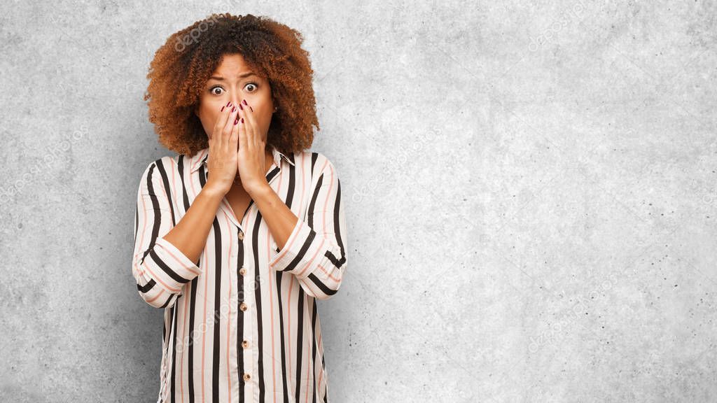 Young black afro woman very scared and afraid hidden