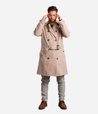 Genç adam giyen bir konsantrasyon jest yapıyor trençkot