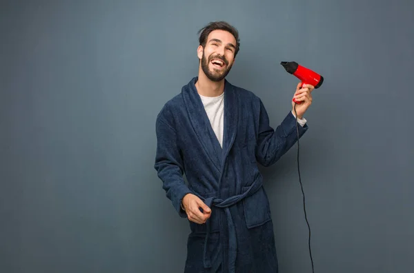 Młody człowiek ubrany piżamy gospodarstwa Fryzjer — Zdjęcie stockowe