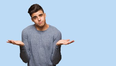 Şüphe ve omuzlarında shrugging genç yakışıklı adam